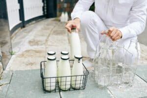 milkman places full bottles on a stoop in a milk run