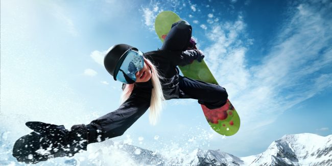 Photo looking up at the face of a snowboarder performing an aerial trick