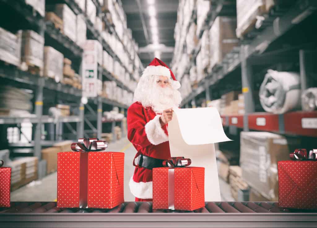 Santa Claus busy with the orders of Christmas gifts in a warehouse